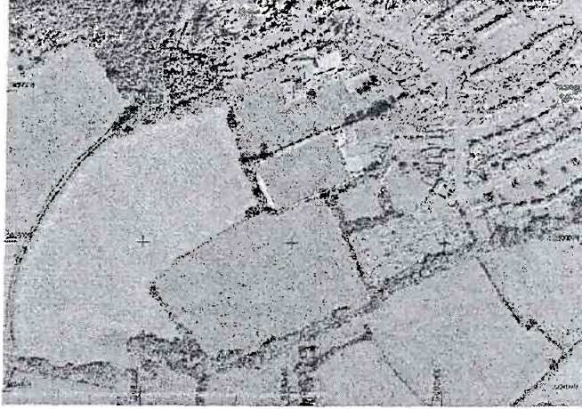 A grainy black and white aerial view or site plan showing field boundaries, hedgerows, and scattered rural buildings with crosshair markers.