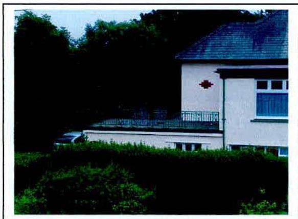 A photograph showing the rear elevation of a white detached house featuring a flat-roofed single-story extension or conservatory structure.