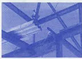 A low-resolution, blue-tinted image showing intersecting wooden beams or joists and a white pipe, likely a view of a ceiling structure.