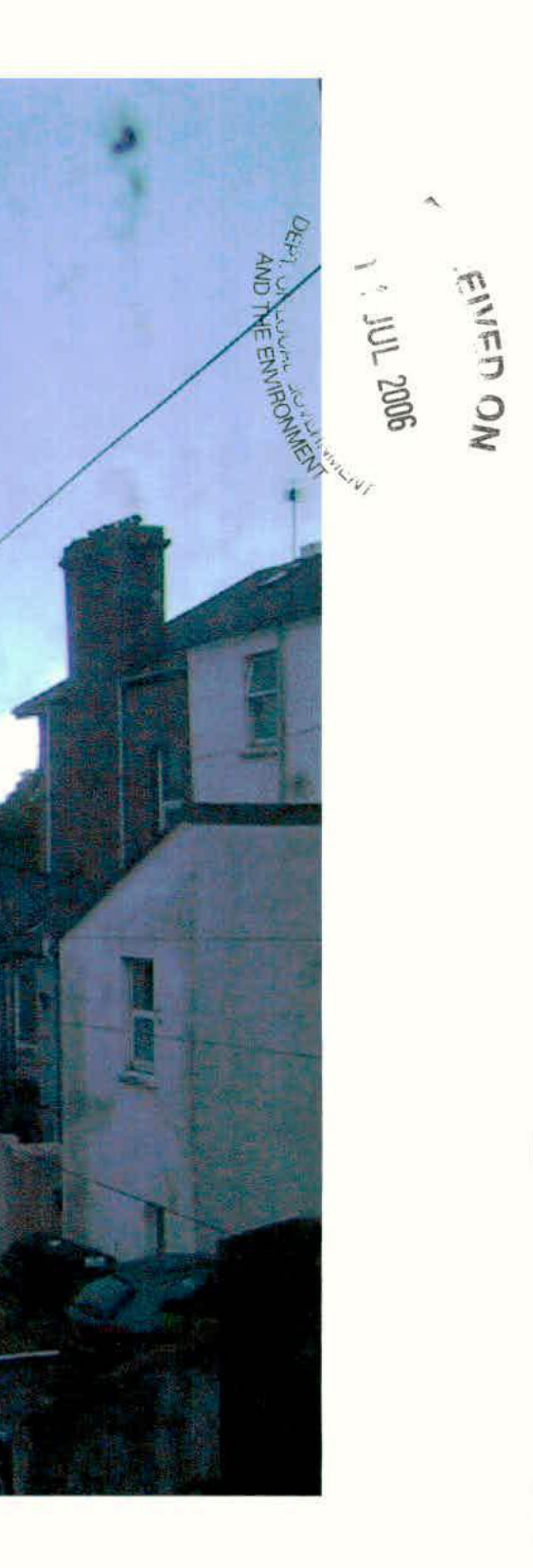 A rotated photograph showing the side elevation of a residential building with a chimney and parked cars, featuring a 'Received' stamp from the Department of the Environment.