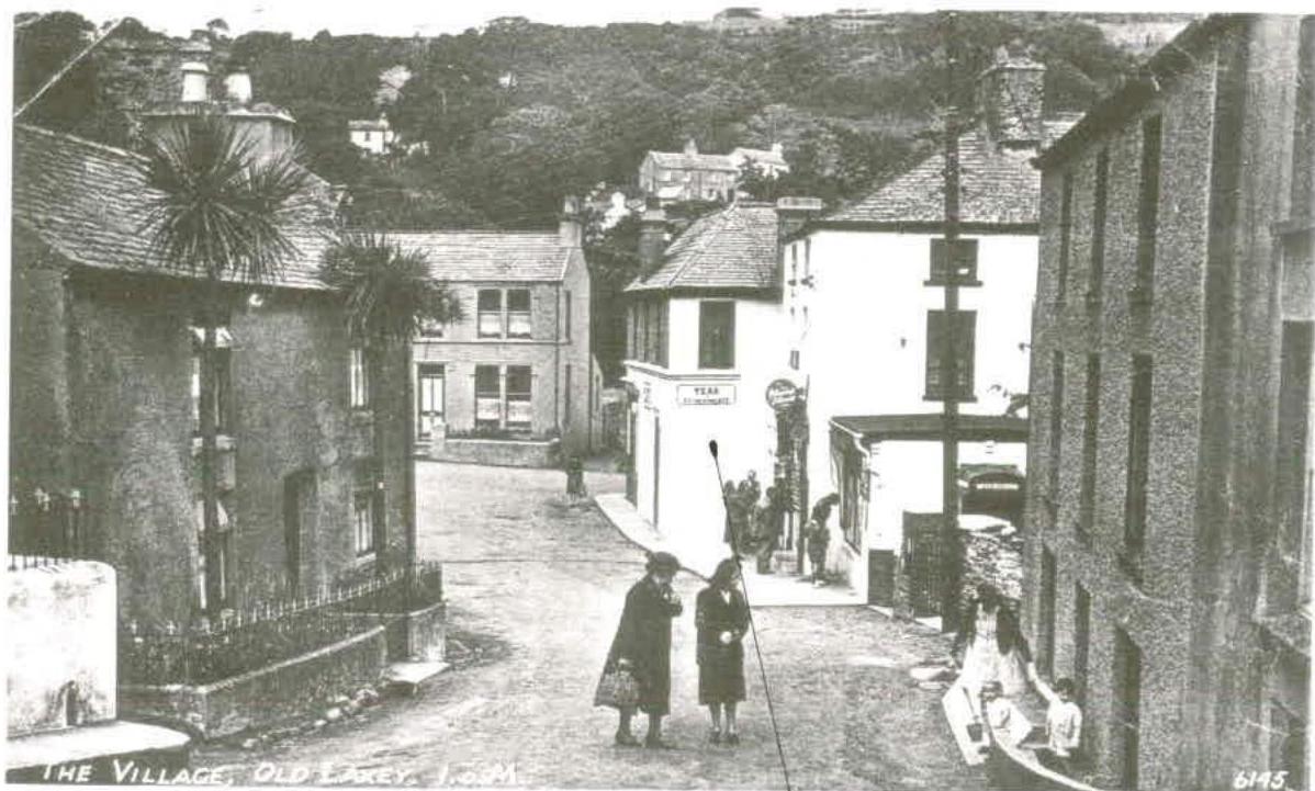 A black and white historical photograph of a street scene in Old Laxey, Isle of Man, featuring stone buildings and a visible 'Tea Room' sign.