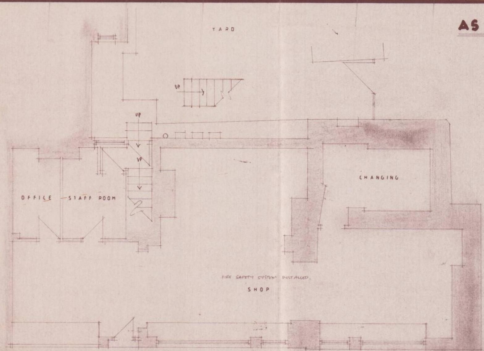 This image displays a scanned architectural floor plan of a commercial property, detailing rooms such as a shop, office, staff room, and changing area with stair access.