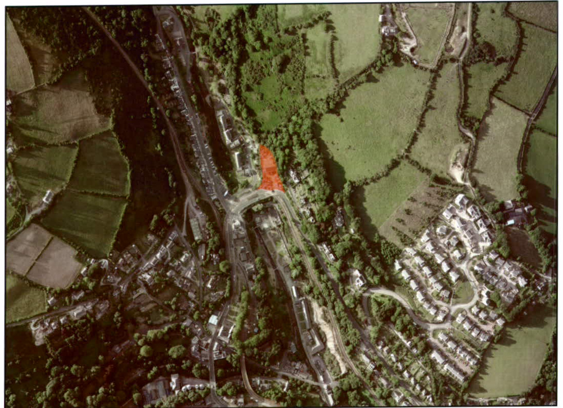 An aerial site location map showing a specific plot of land highlighted in orange, surrounded by fields, roads, and residential housing.