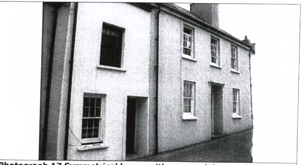 A black and white photograph showing the exterior facade of a two-story building, featuring a mix of architectural styles with a smoother rendered section on the left and traditional sash windows on the right.