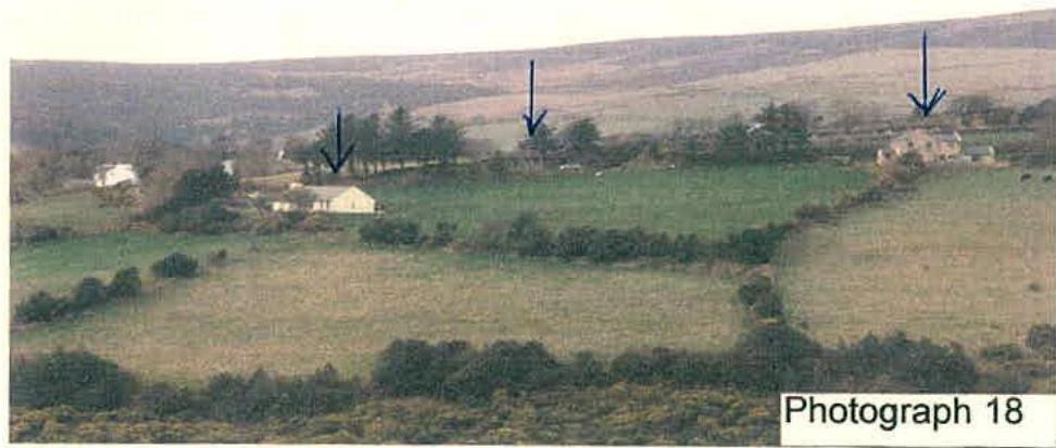 A rural landscape photograph showing fields and distant buildings with arrows indicating specific sites or structures.