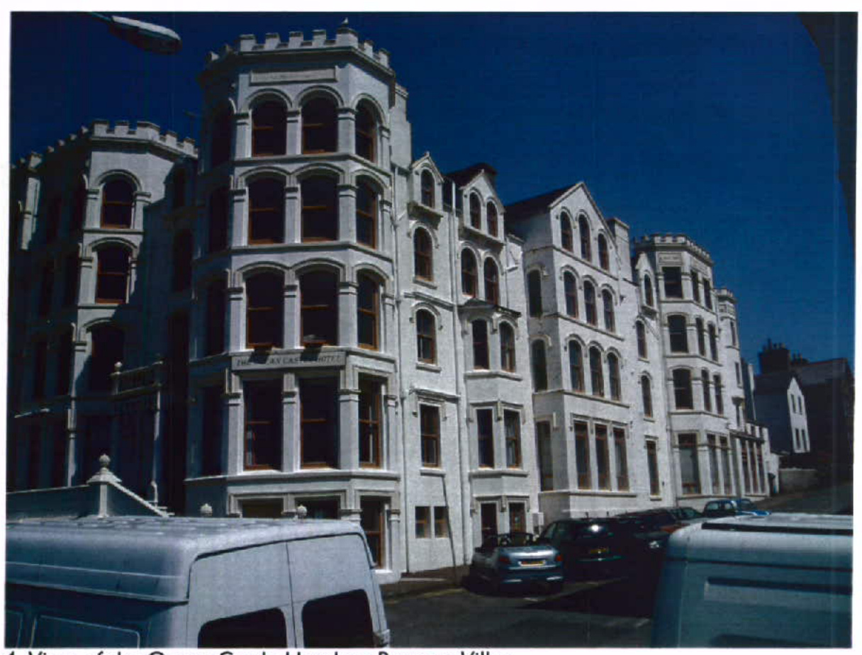 A photograph of a large, white, multi-story building with distinctive castle-like turrets and arched windows, with vehicles parked in the foreground.