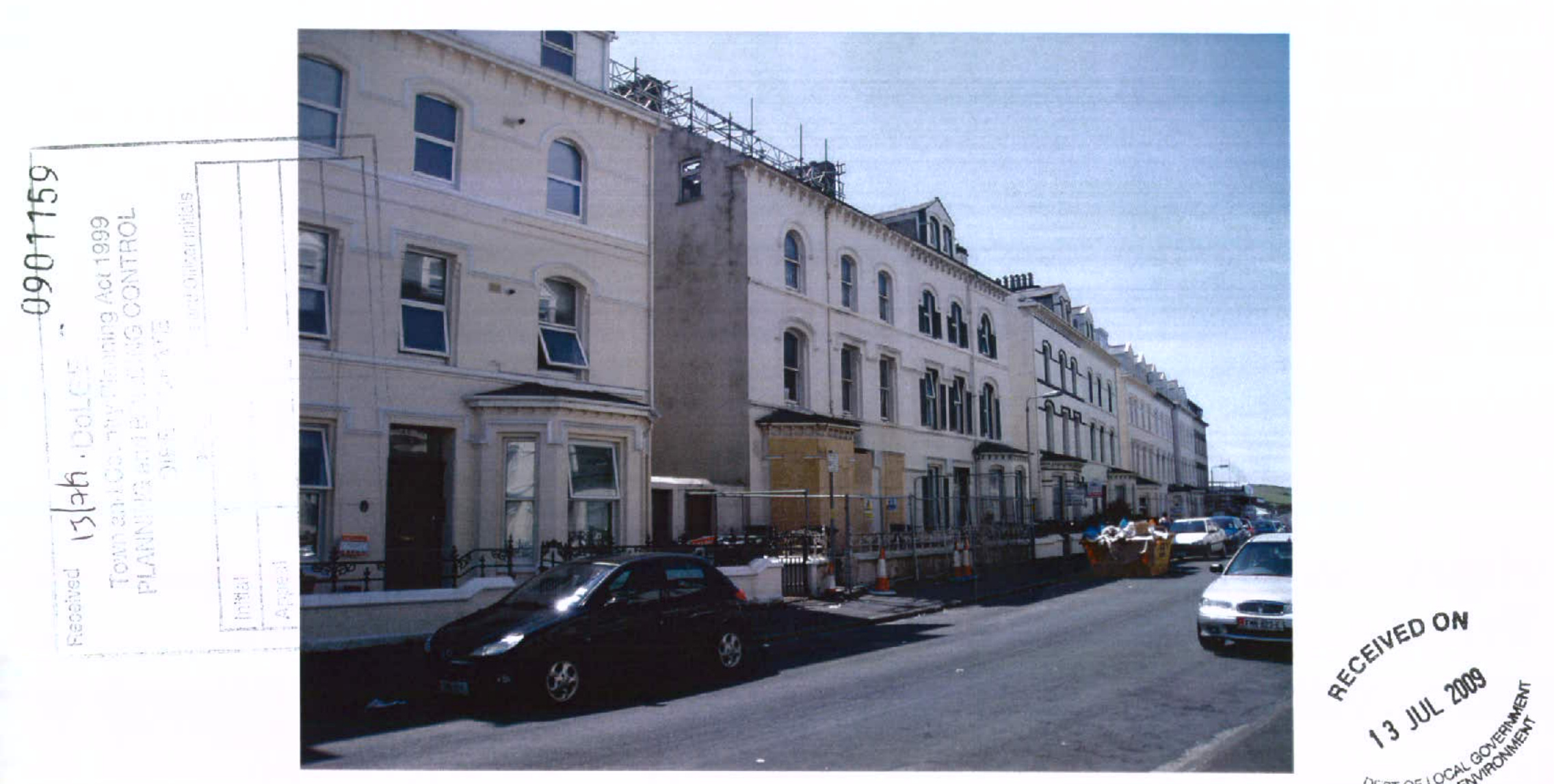 A street-level photograph showing a row of white terraced buildings, with scaffolding visible on one roof indicating renovation work.
