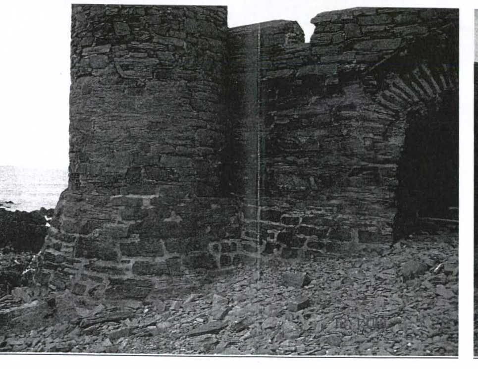 A black and white photograph depicting the stone masonry of a historic coastal structure, showing a round tower and an arched opening amidst rubble.