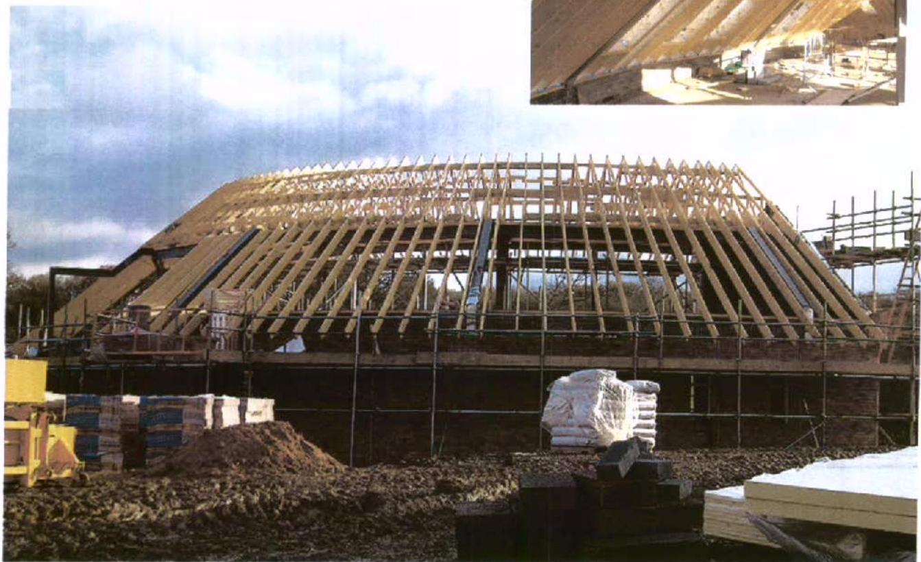 A photograph showing a large timber-framed building under construction with a distinctive curved roof structure and scaffolding.