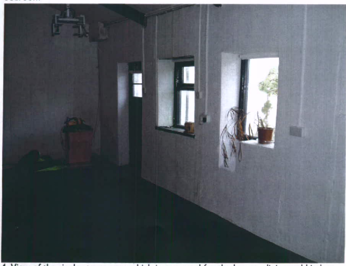 Interior photograph of a room with white walls and windows, likely showing the ground floor of the outbuilding being converted into an apartment.