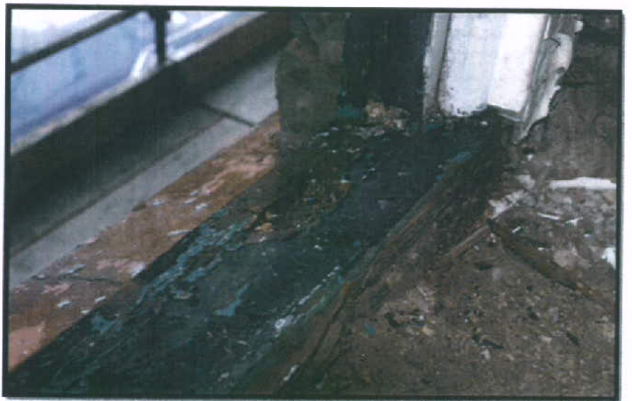 A close-up photograph showing a damaged and rotting wooden window sill with peeling paint, likely documenting the condition of an existing window prior to replacement.