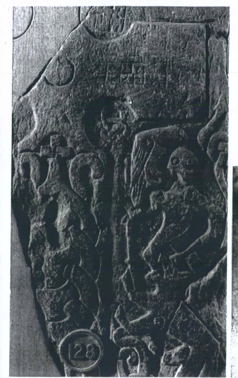 A black and white photograph of an ancient carved stone slab featuring intricate Celtic knotwork and figures, likely serving as a reference for the proposed replica keeill.