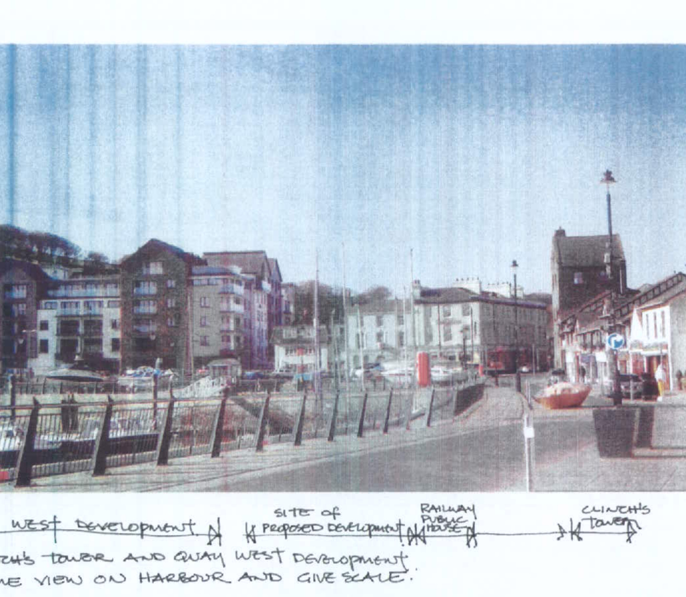 A grainy photograph of a harbor street scene with buildings and a waterfront railing, featuring handwritten annotations identifying a proposed development site.