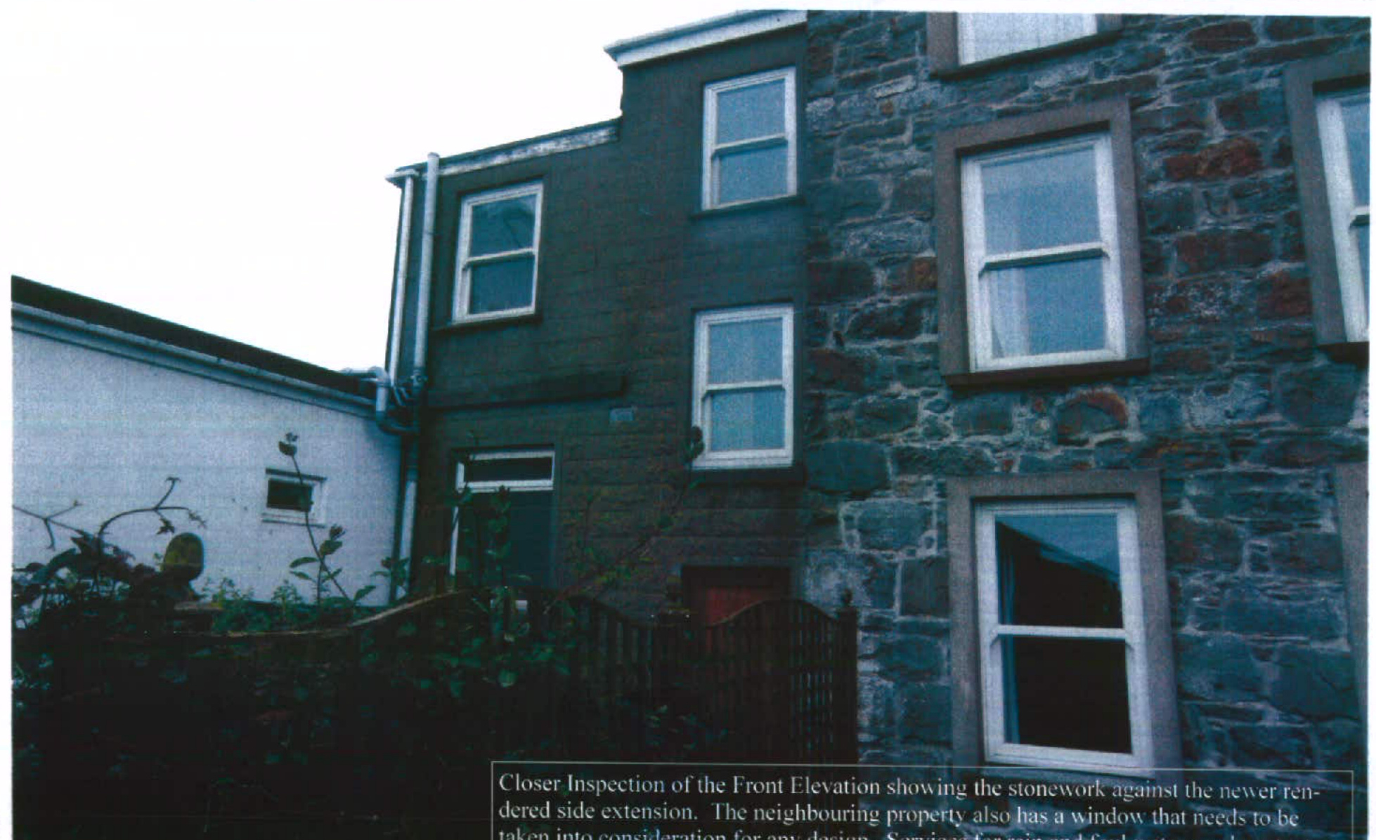 A photograph showing the front elevation of a stone building, highlighting the contrast between the original stonework and a newer rendered side extension.