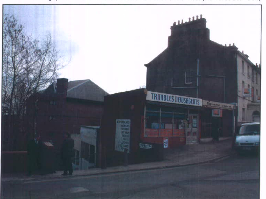 A street-level photograph showing a newsagents shop named 'Trimbles Newsagents' with a smaller attached structure and a taller brick building behind it.