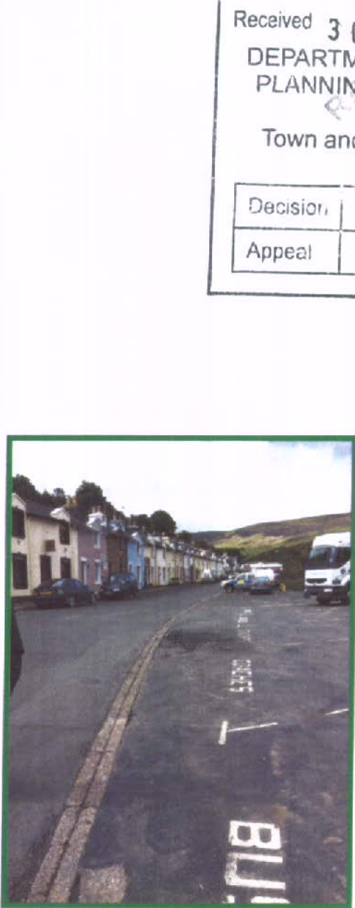 A photograph showing a street scene with a row of colorful terraced houses on the left and a paved parking area with white road markings in the foreground, with a partial planning document header visible at the top.