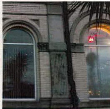 A photograph showing the exterior facade of a building with two large arched windows and light-colored stonework.