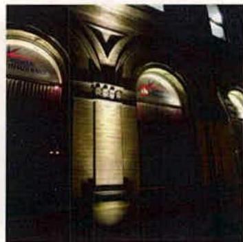 A night-time photograph showing the illuminated facade of a building with arched windows and architectural details.