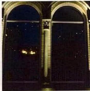 A night-time photograph showing the illuminated stone arches of a building facade, likely demonstrating the effect of external lighting.