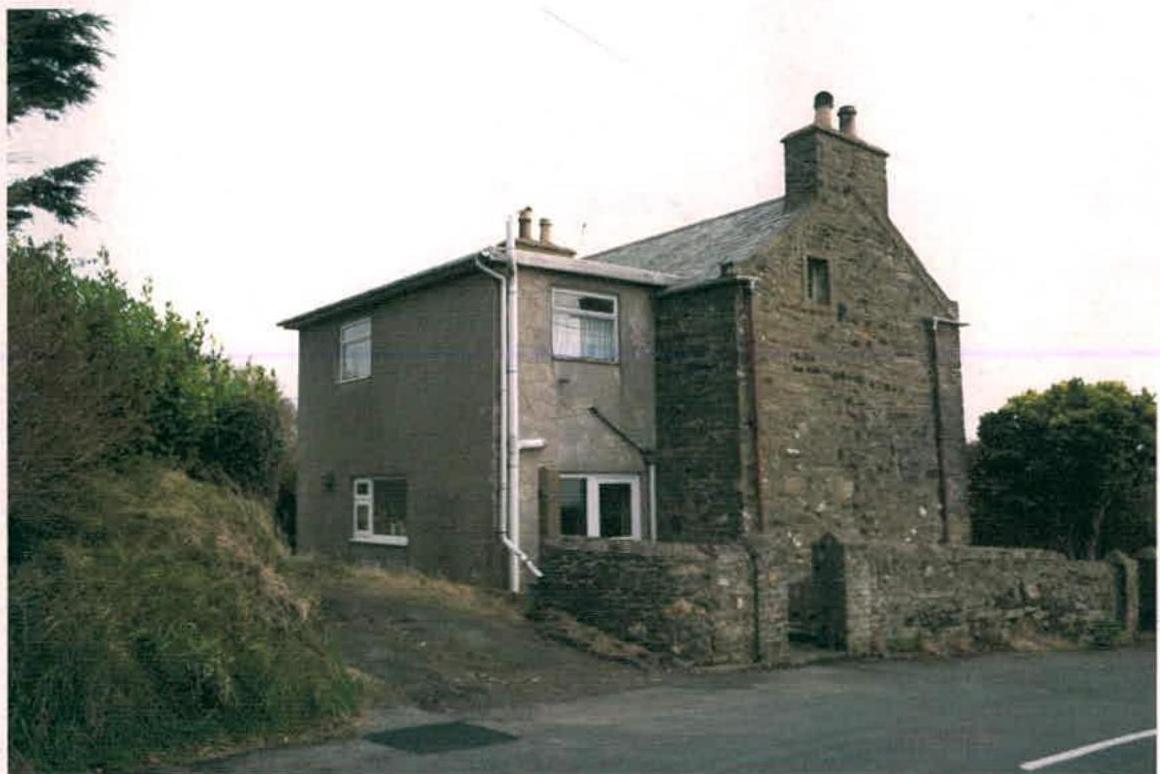 A photograph of a two-storey dwelling featuring a mix of original stone construction and a newer rendered extension section.