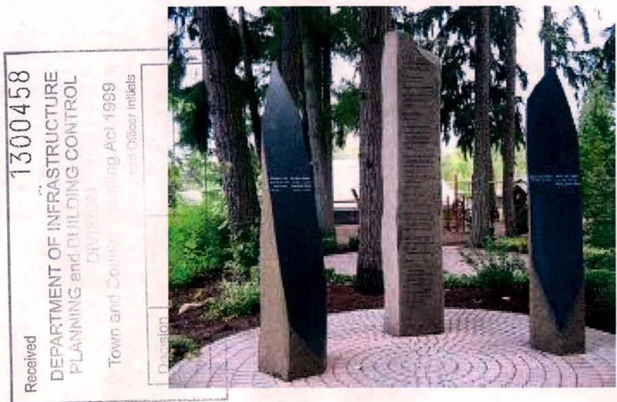A planning document page displaying a photograph of three tall stone memorial pillars arranged on a paved circular area surrounded by trees and greenery.