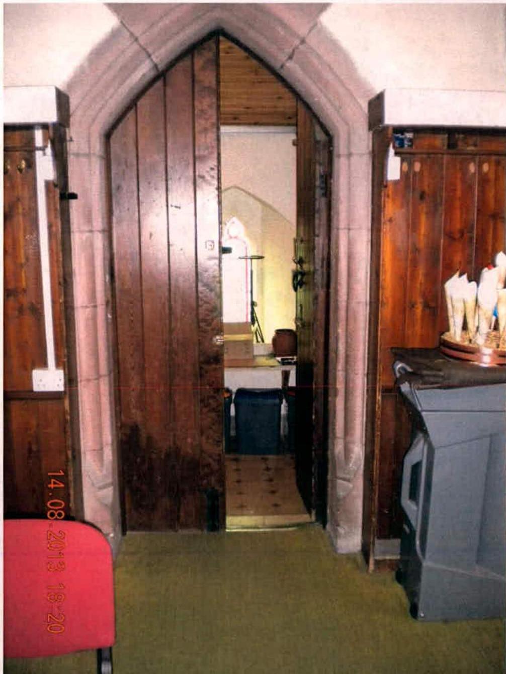 Interior photograph showing a stone arched doorway leading into a room with religious features, likely a prayer room.