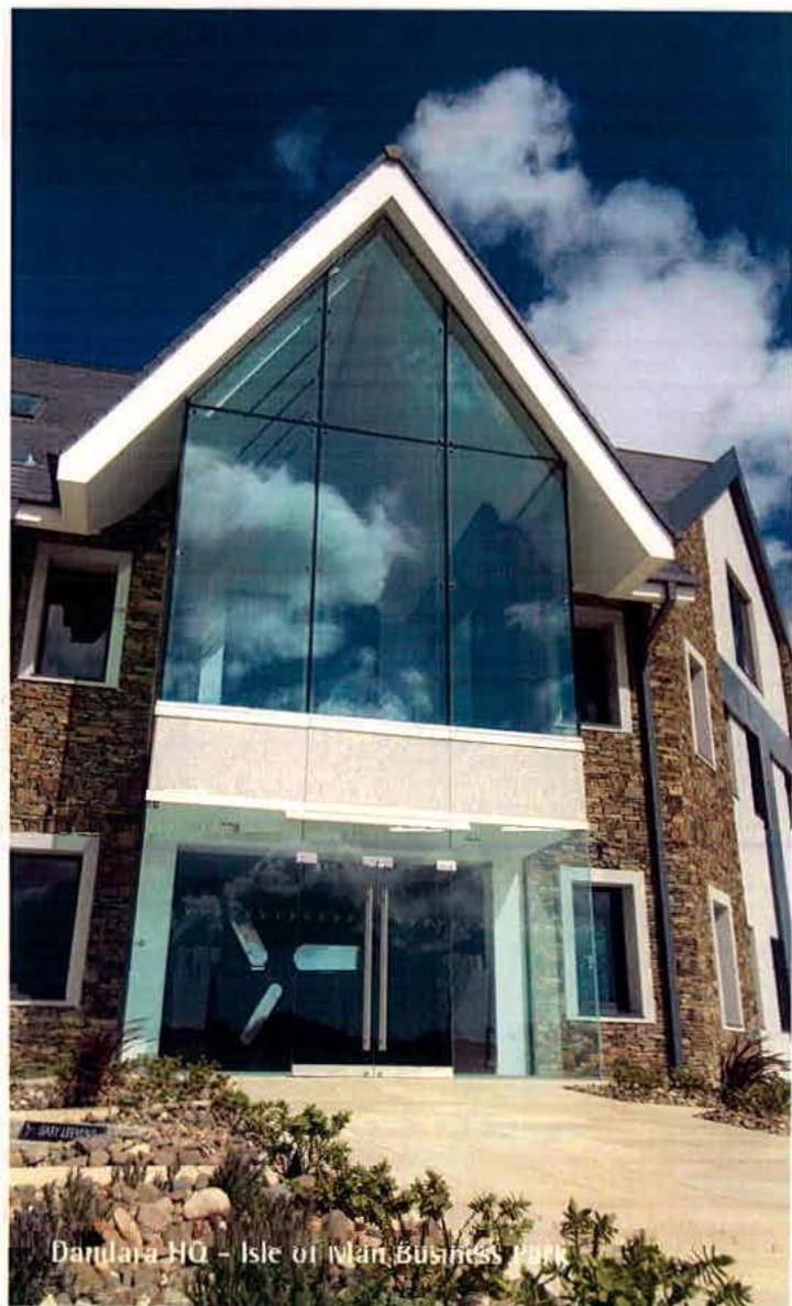 A photograph of a modern commercial building featuring a large triangular glass gable and stone cladding.