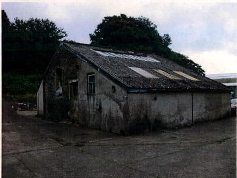 A photograph showing a dilapidated, single-story outbuilding with a weathered roof and walls, likely the laundry building proposed for demolition.
