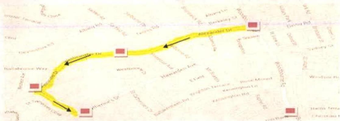 A street map displaying a highlighted yellow route with directional arrows and red square markers, likely indicating a specific path or site boundary.