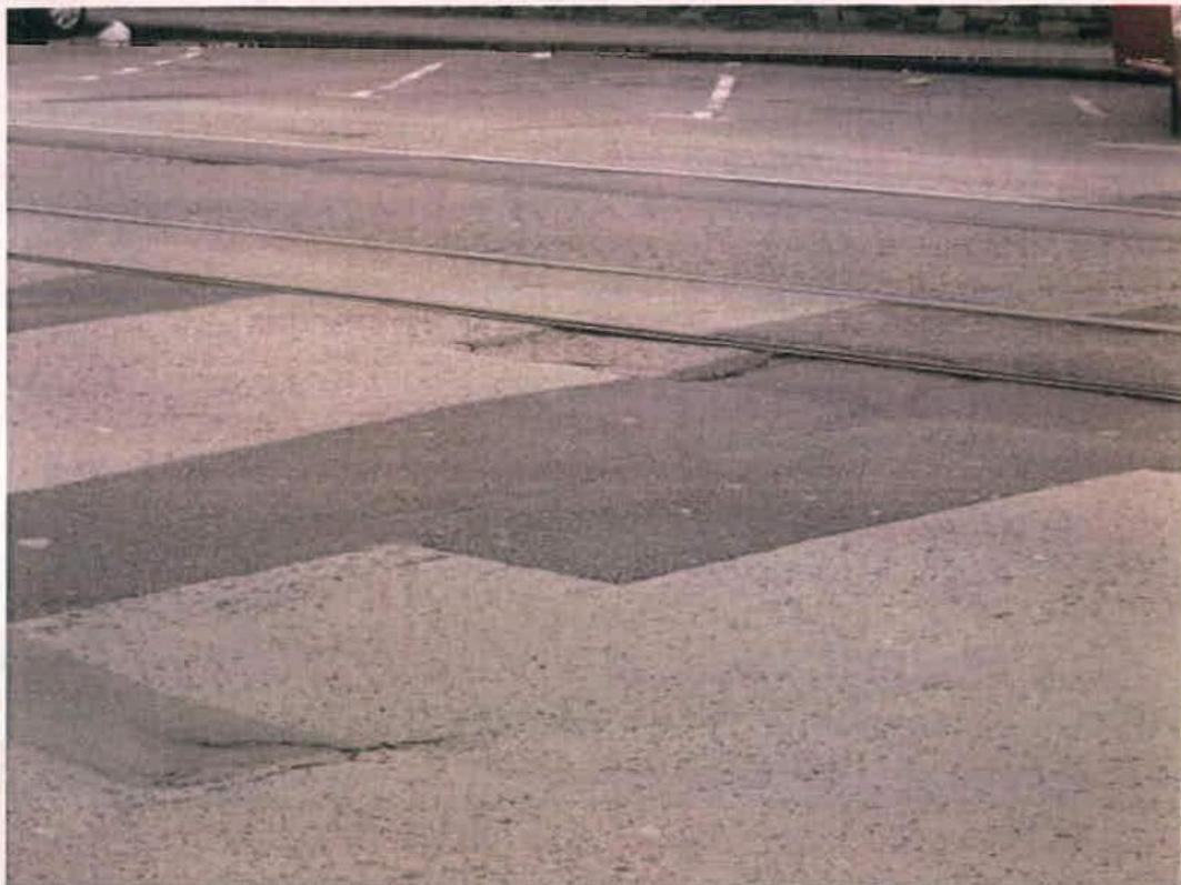 A ground-level photograph of the Douglas Promenade surface showing tram tracks and white painted road markings.