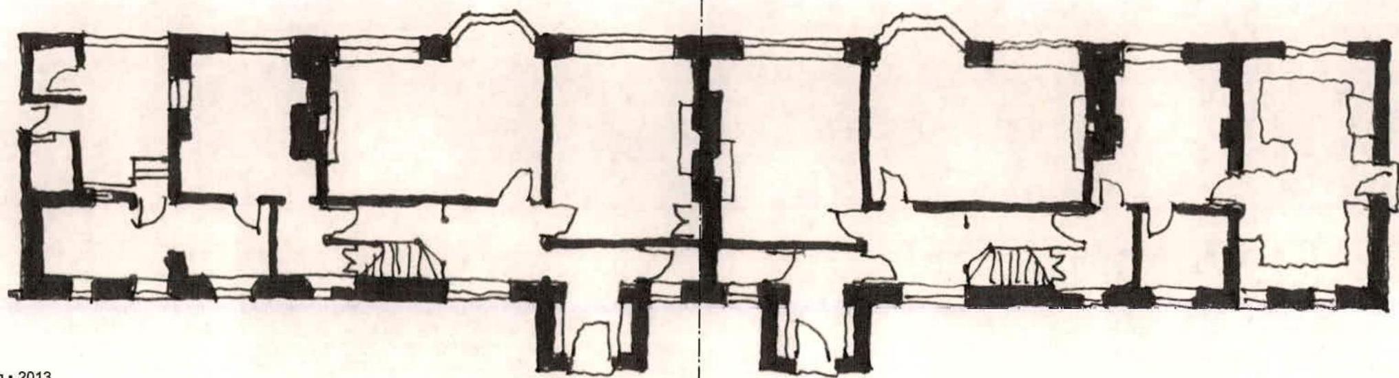 This image displays a black and white architectural floor plan showing the internal layout of a long building with multiple rooms, walls, and staircases.