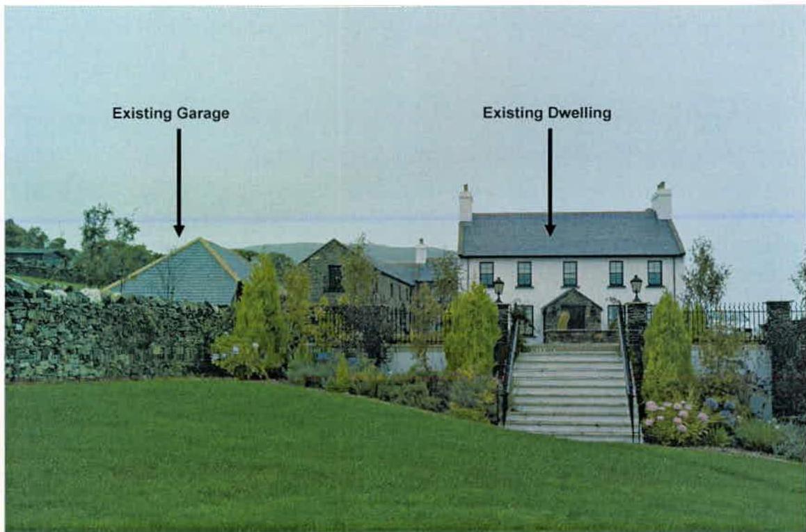 A photograph showing the existing detached dwelling and a separate garage structure on a rural property, with text labels identifying each building.