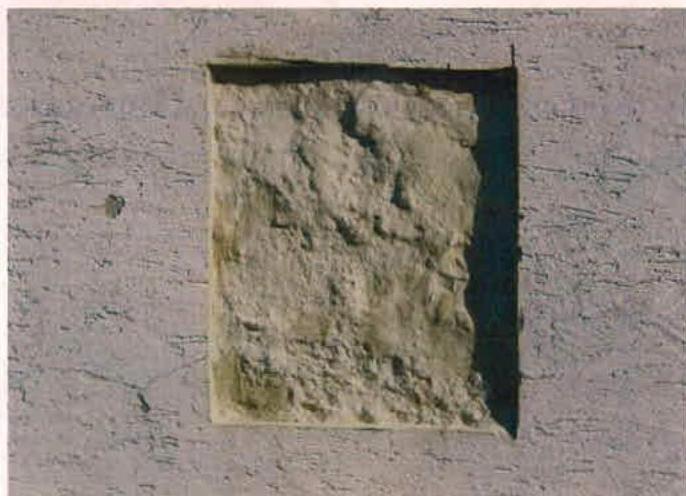 A close-up photograph showing a rectangular recess or blocked opening in a rendered masonry wall.