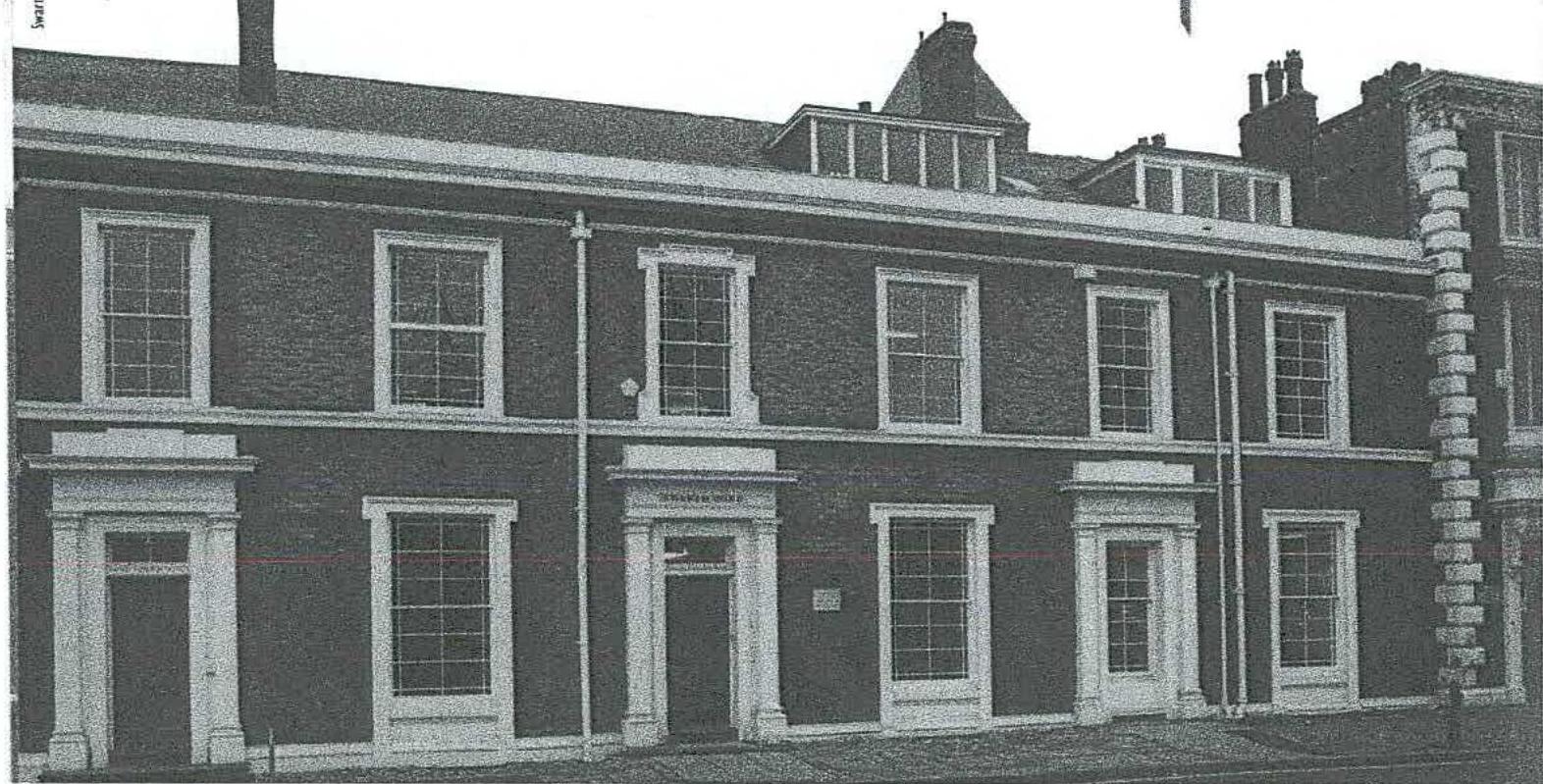 A grainy black and white photograph showing the front elevation of a historic terraced building with sash windows and pedimented doorways.