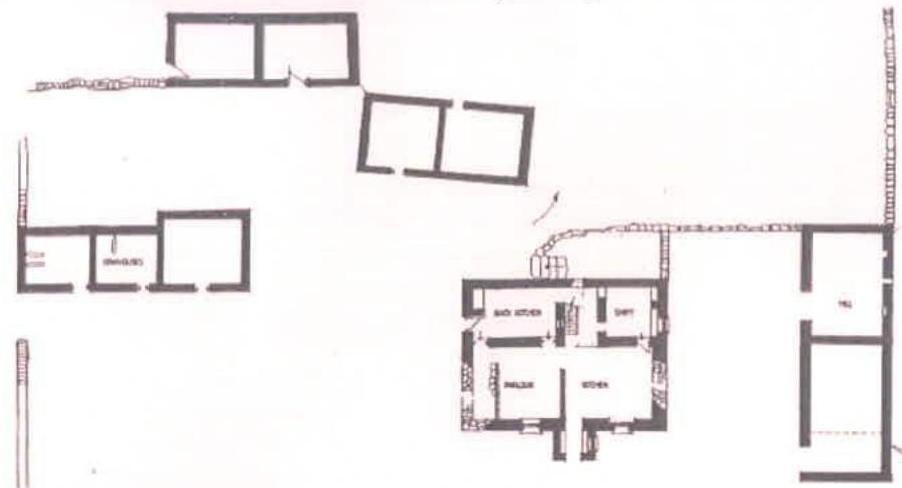 This is a black and white architectural drawing showing the floor plan of a main cottage and the footprints of separate outbuildings. It labels internal rooms like a kitchen and bedroom, as well as structures such as...