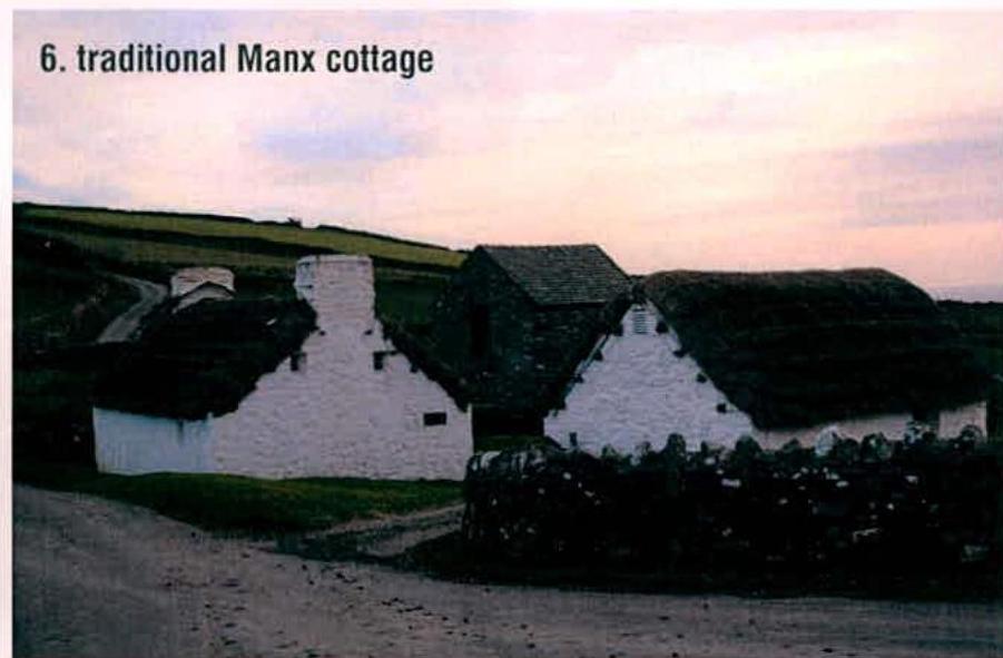A photograph showing a cluster of traditional white-washed stone buildings with slate roofs in a rural landscape.