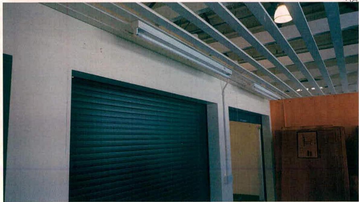 Interior photograph of a commercial space featuring exposed ceiling beams and a large roller shutter door.