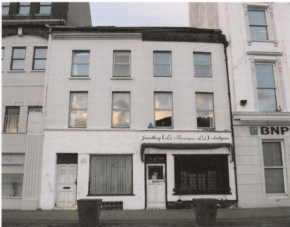 A street-level photograph of a white, three-story terraced building featuring a shop front labeled 'Jewellery (La Boutique Ltd) Antiques' next to a BNP bank branch.