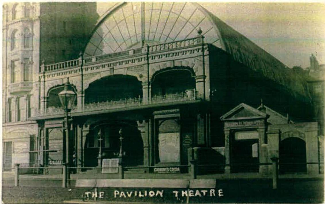 A vintage sepia-toned photograph showing the exterior facade of The Pavilion Theatre, featuring a large arched roof structure and ground-level arches.