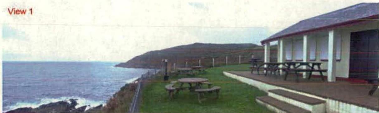 A photograph showing a single-story building with a veranda and picnic tables situated on a grassy slope overlooking the sea.