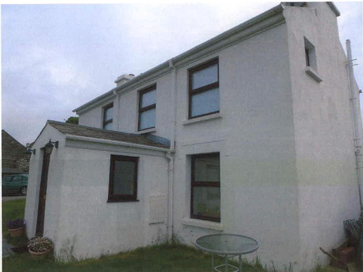 A photograph showing the exterior of a white, two-story detached house with a single-story extension attached to the left side.