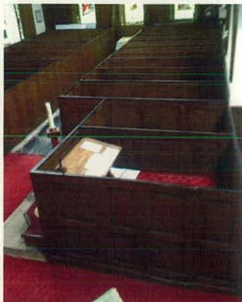 The image shows the interior of a building, likely a church, with rows of wooden pews and red carpeting, serving as a baseline photo for the proposed internal alterations.