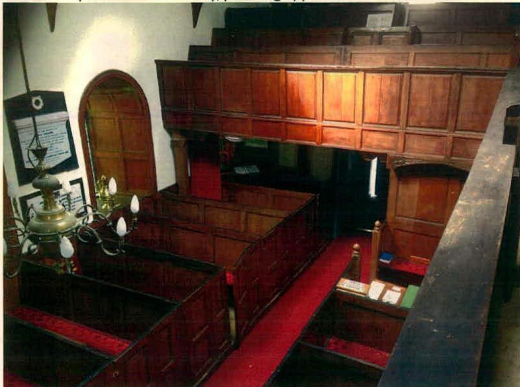 Interior photograph of a historic building featuring extensive wooden paneling, pews, and a gallery loft, likely a chapel or meeting hall.
