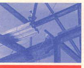 A grainy, blue-tinted photograph showing a steel framework structure, likely roof trusses or beams, with figures visible on the beams during construction.