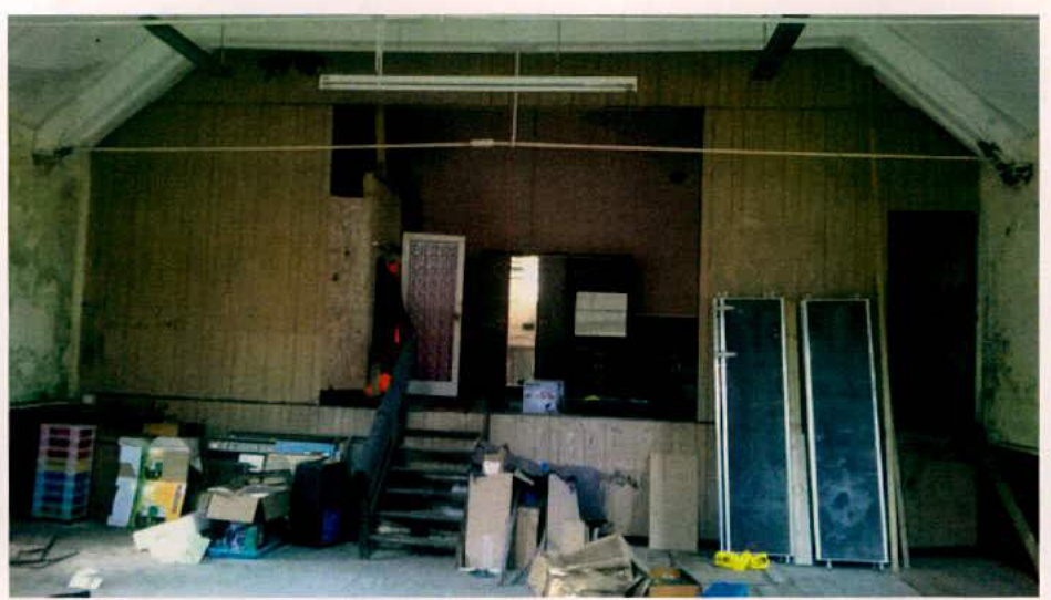 The image shows the interior of a large room with wooden paneling and a staircase, likely depicting the existing condition of a property proposed for conversion.