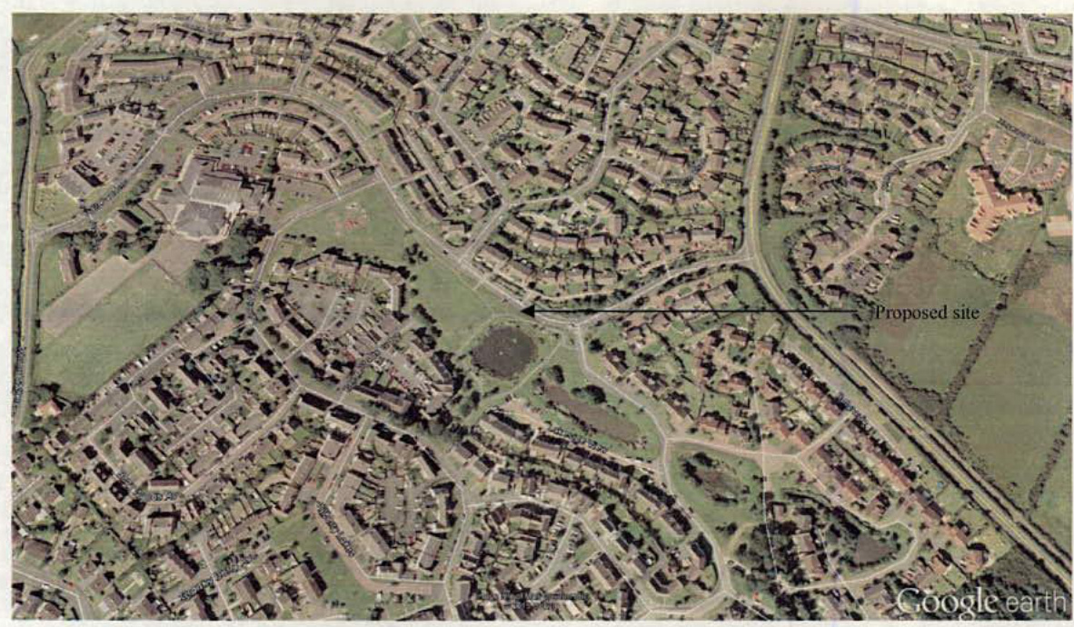 An aerial Google Earth view displaying a residential neighborhood with a black arrow pointing to the 'Proposed site' location near a road junction.