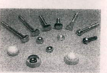 A grainy black and white photograph showing a collection of metal bolts, screws, and nuts arranged on a surface, likely detailing the fixings for the proposed play equipment.