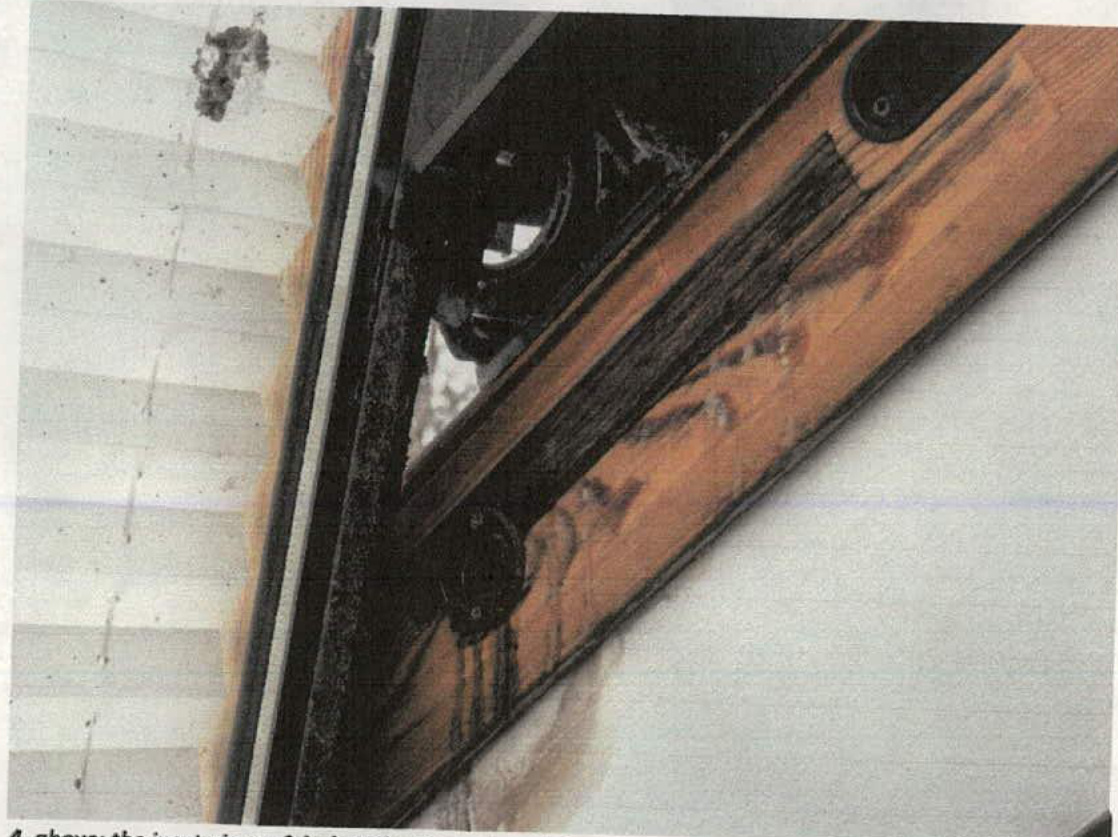 A close-up photograph of a roof structure showing wooden rafters and white tiles/slates.
