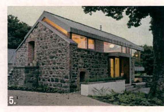 A photograph of a stone building, likely a barn conversion, featuring a modern extension with large windows and a pitched roof.
