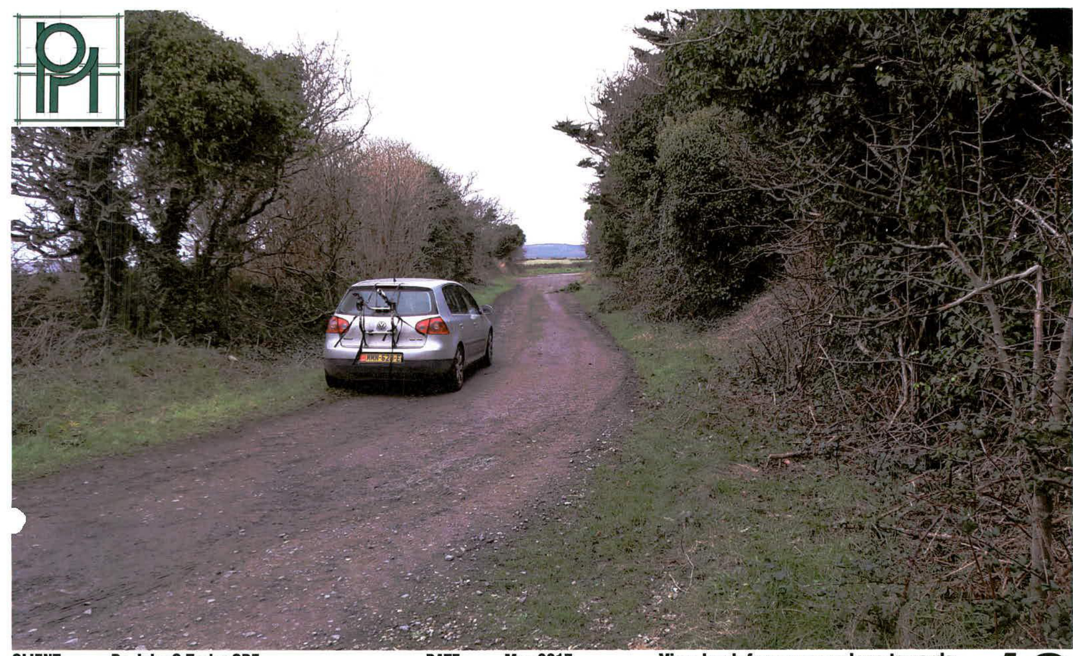 A photograph showing a rural dirt track with a silver car parked on the side, flanked by dense vegetation and leading towards a coastal view in the distance.